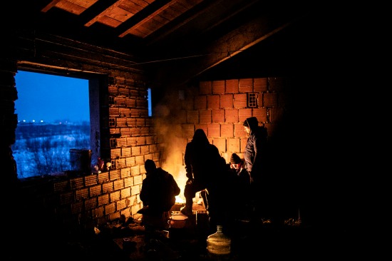 Refugees from Afghanistan and Pakistan warm themselves by a fire.