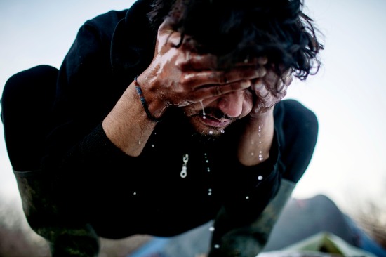 An Afghan refugee washes his face.