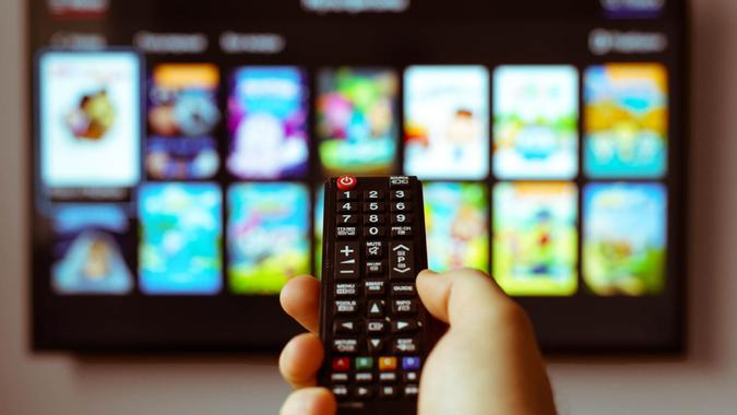 Male hand holding TV remote control.